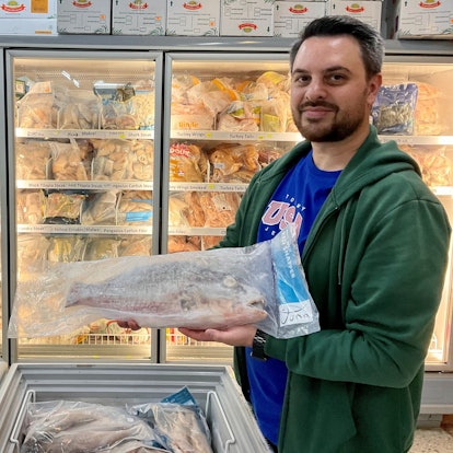 Mann mit einem eingepackten, tiefgefrorenen Fisch