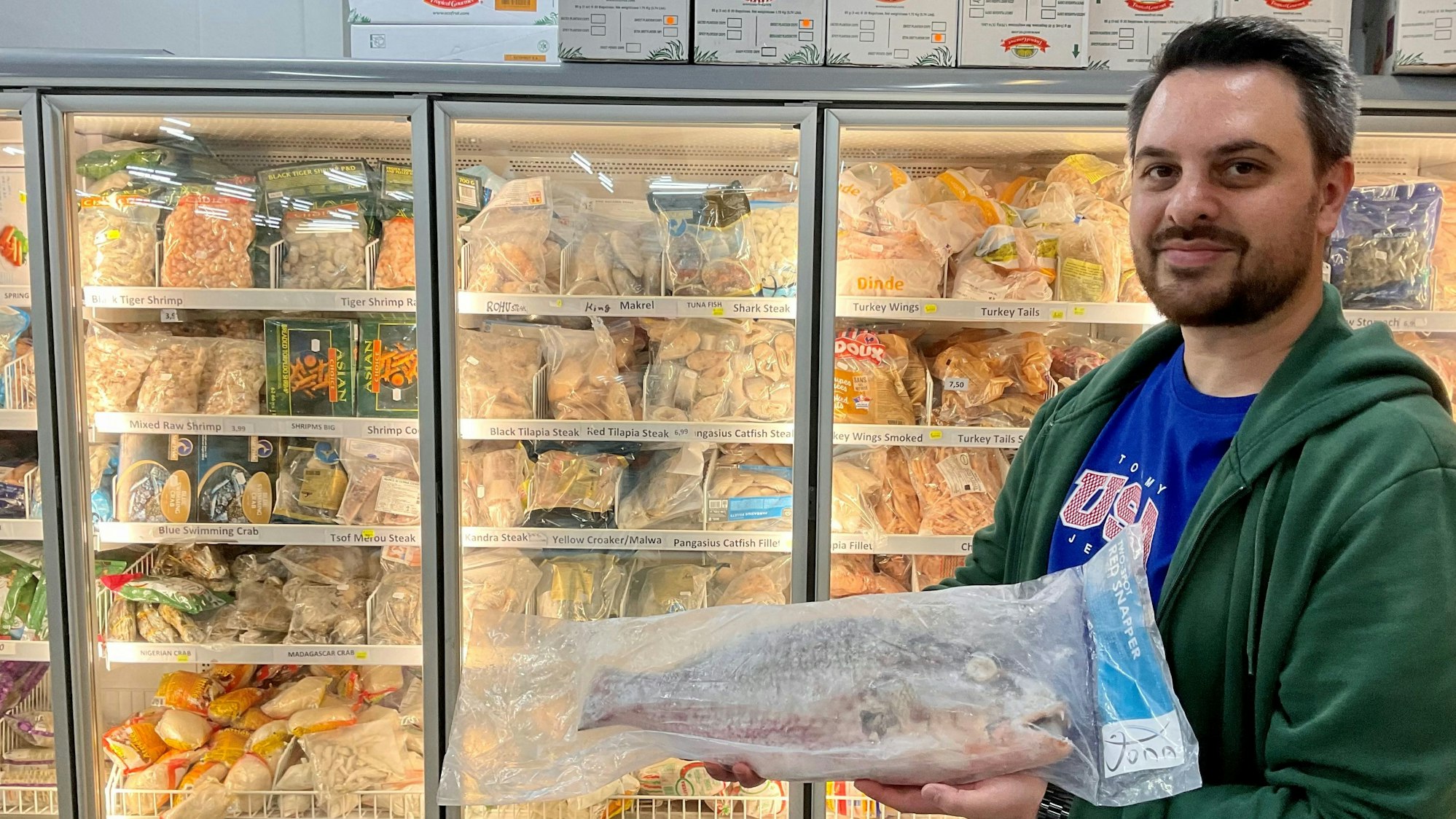 Mann mit einem eingepackten, tiefgefrorenen Fisch