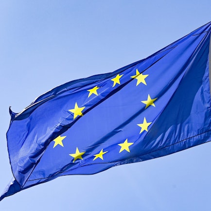 Eine Europaflagge weht vor blauem Himmel.
