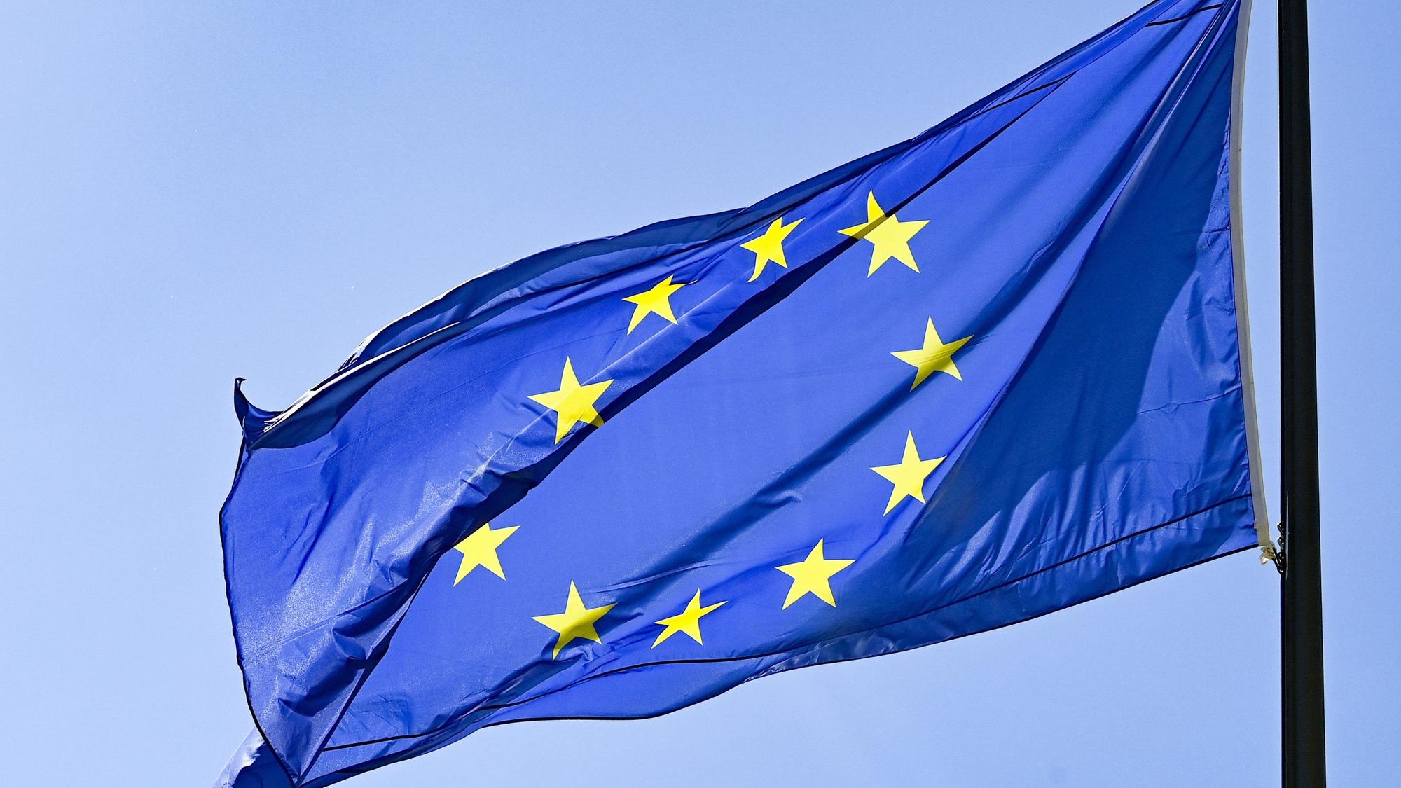 Eine Europaflagge weht vor blauem Himmel.