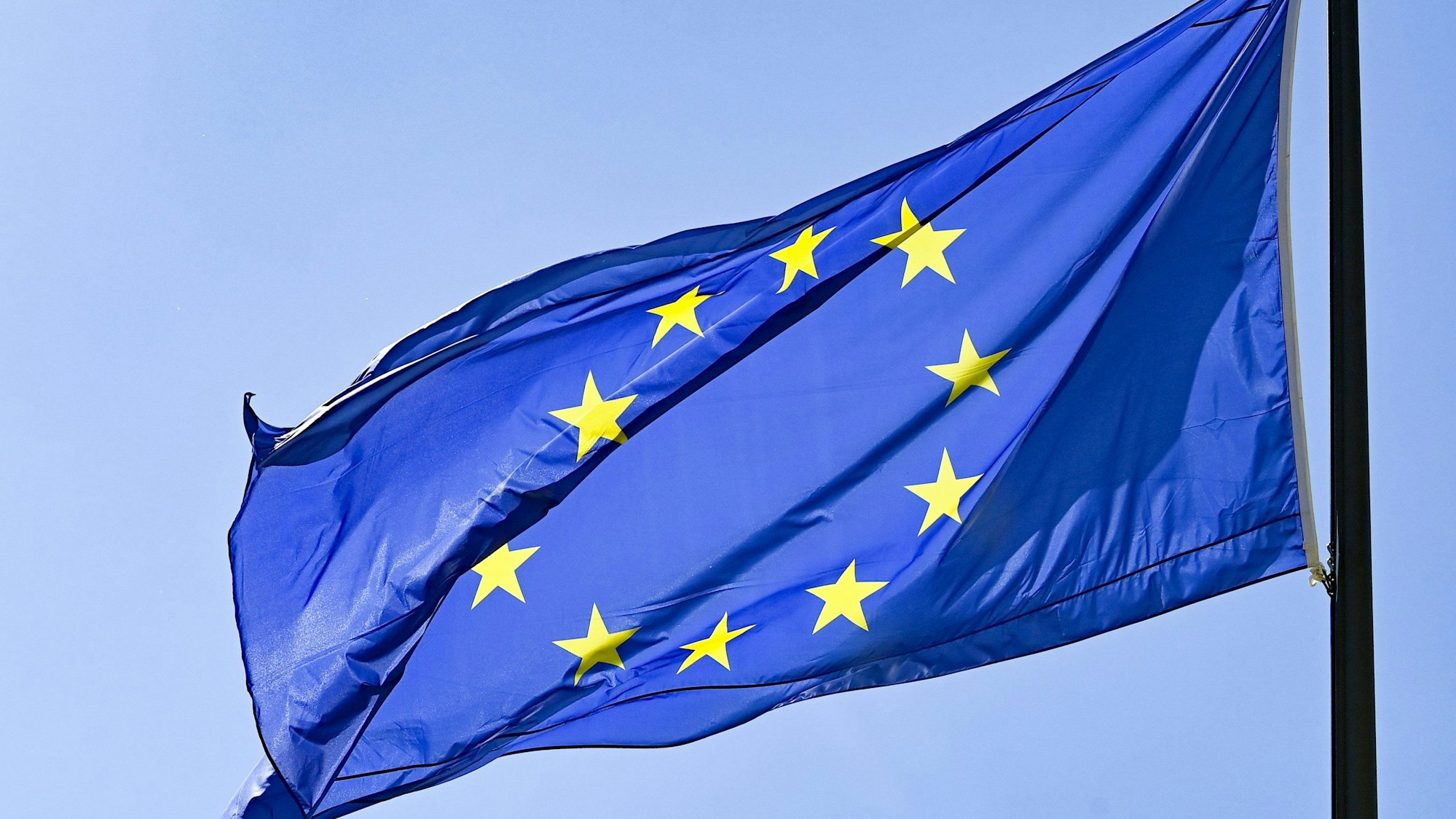 Eine Europaflagge weht vor blauem Himmel.