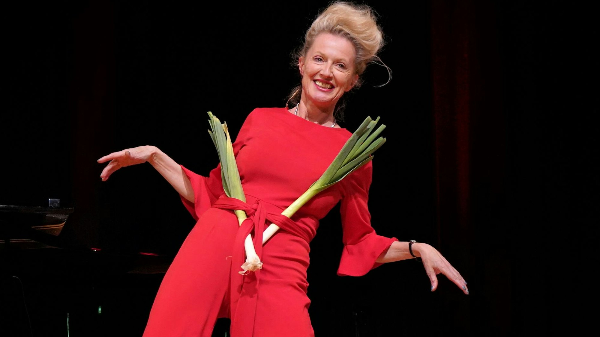 Katharina Hoffmann moderierte den Abend im Stadttheater Euskirchen. Dabei führte sie einen Fruchtbarkeitstanz auf, für den sie sich zwei Stangen Lauch in den Gürte ihres roten Outfits gesteckt hat.