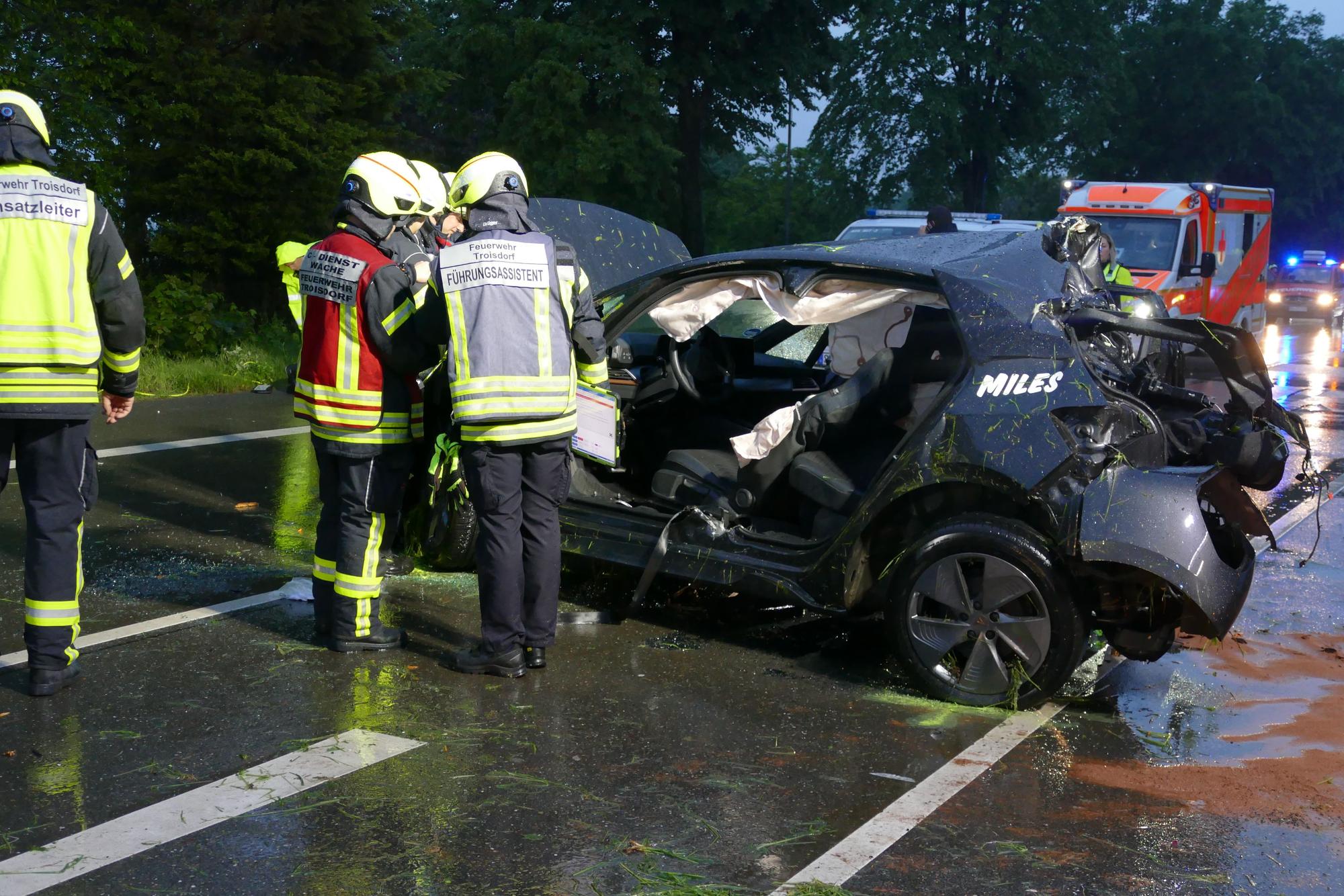 Feuerwehrleute neben einem Auto ohne Türen.