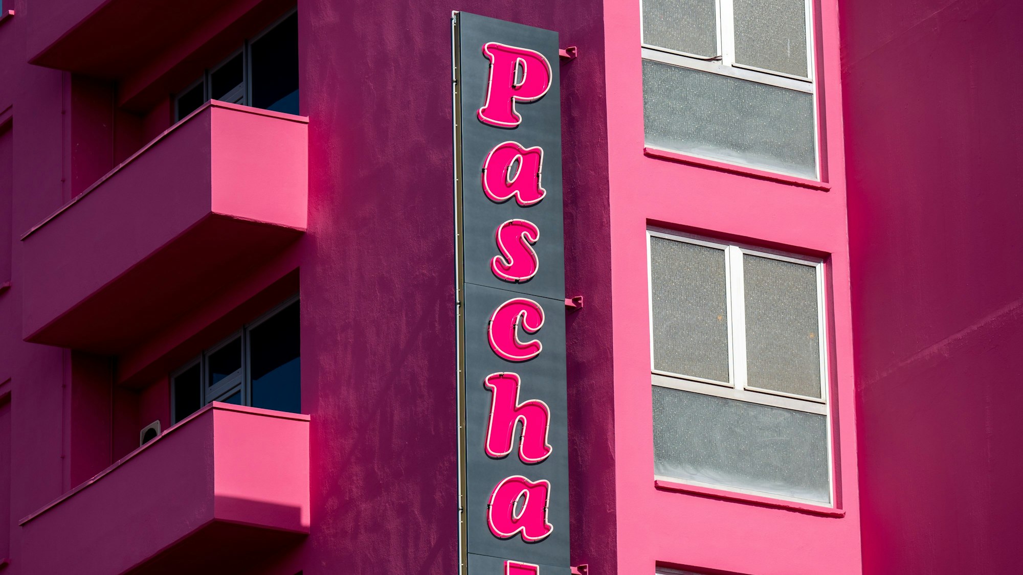 Das Bordell ist von der Seite zu sehen mit Schriftzug und pinkfarbener Fassade.