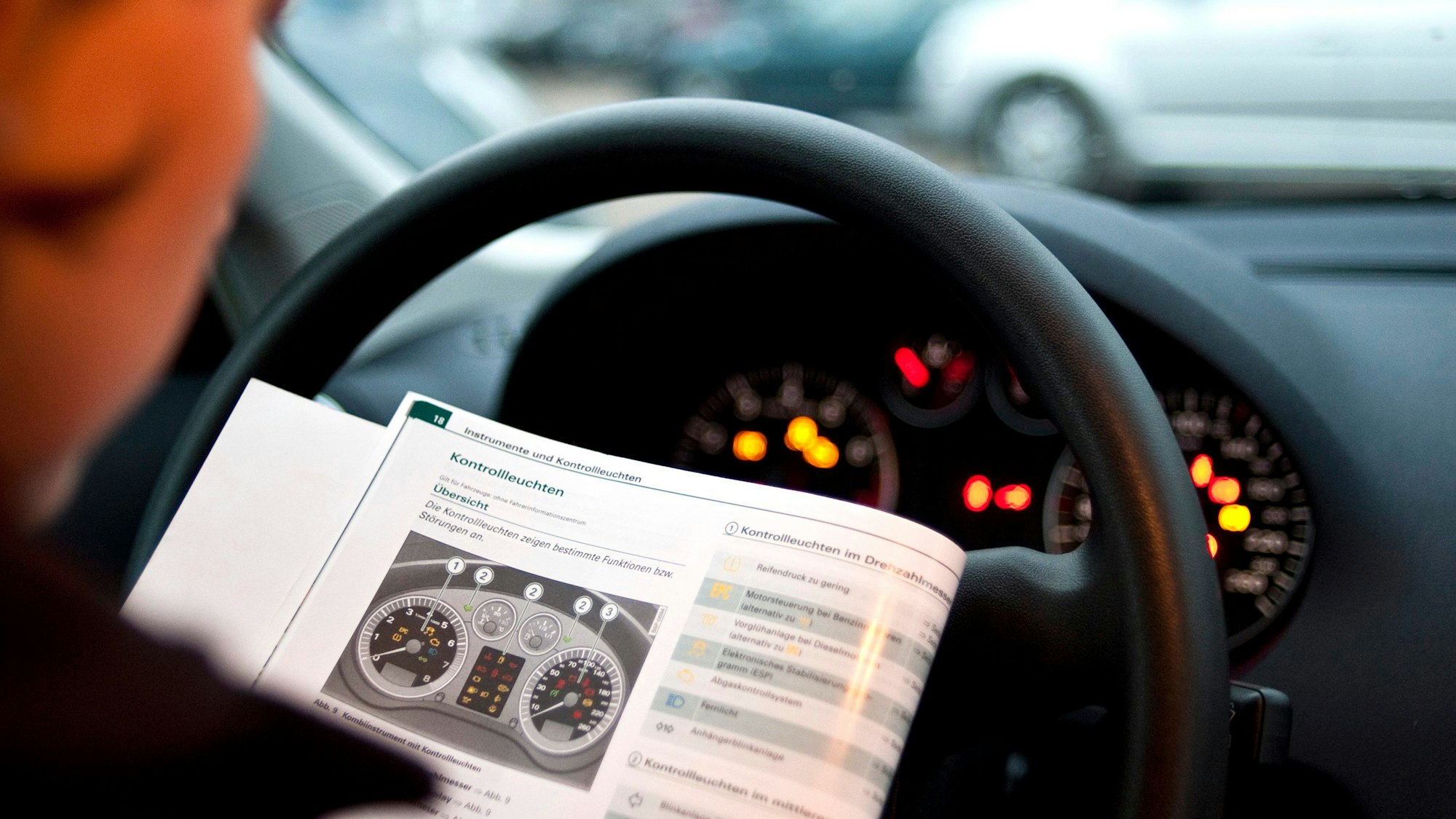 Ein Autofahrer studiert die Bedienungsanleitung hinter dem Steuer seines Wagens.