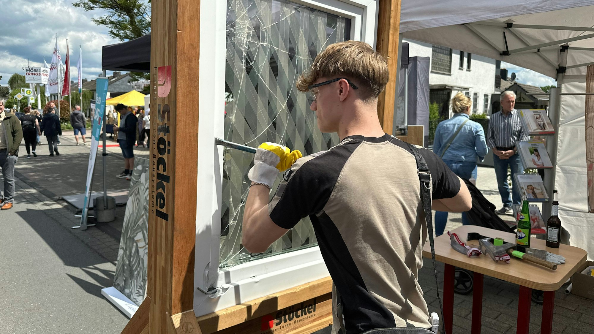 Auszubildender Julien Färfers aus der Schreinerei Frings zeigt an einem geschlossenen Fenster wie gut Diebstahlsicherungen sind.
