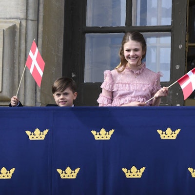 Prinz Oscar und Prinzessin Estelle winken mit dänischen Fahnen.