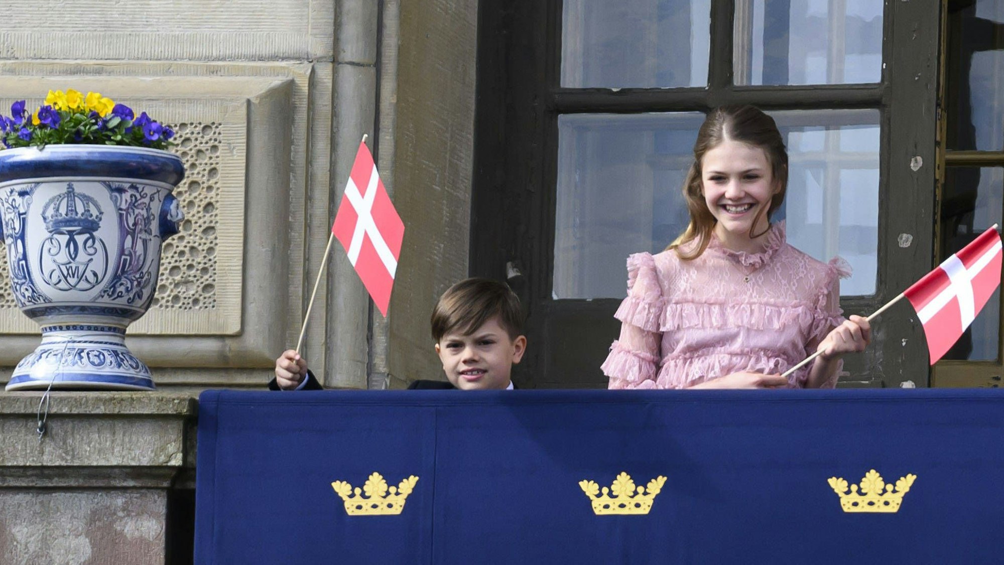 Prinz Oscar und Prinzessin Estelle winken mit dänischen Fahnen.
