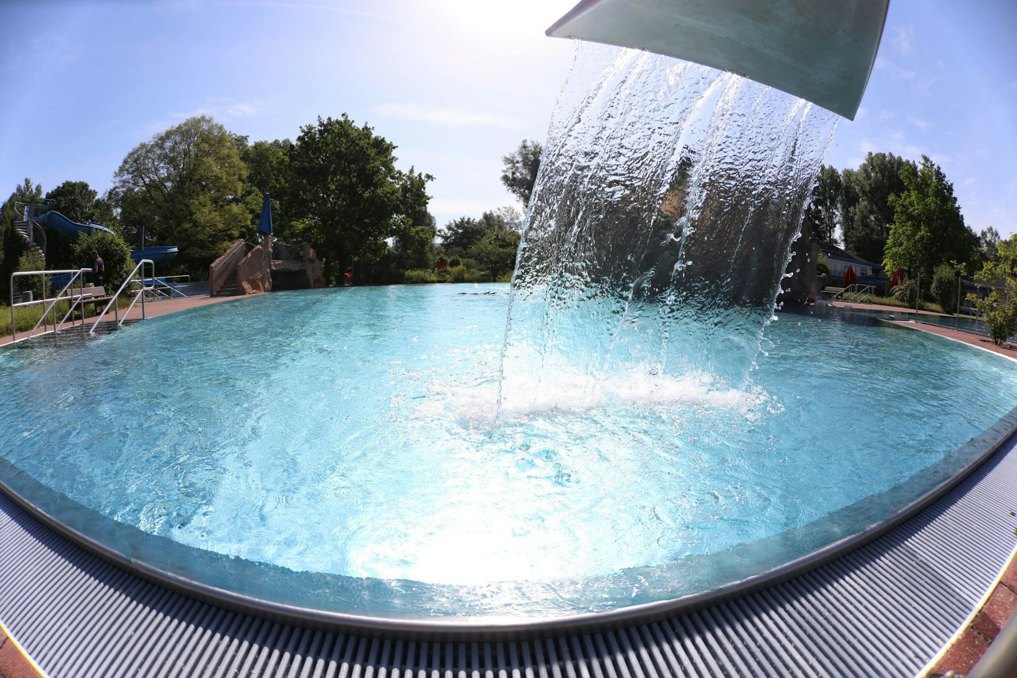 Ein breiter Wasserstrahl fließt in ein Schwimmbecken.