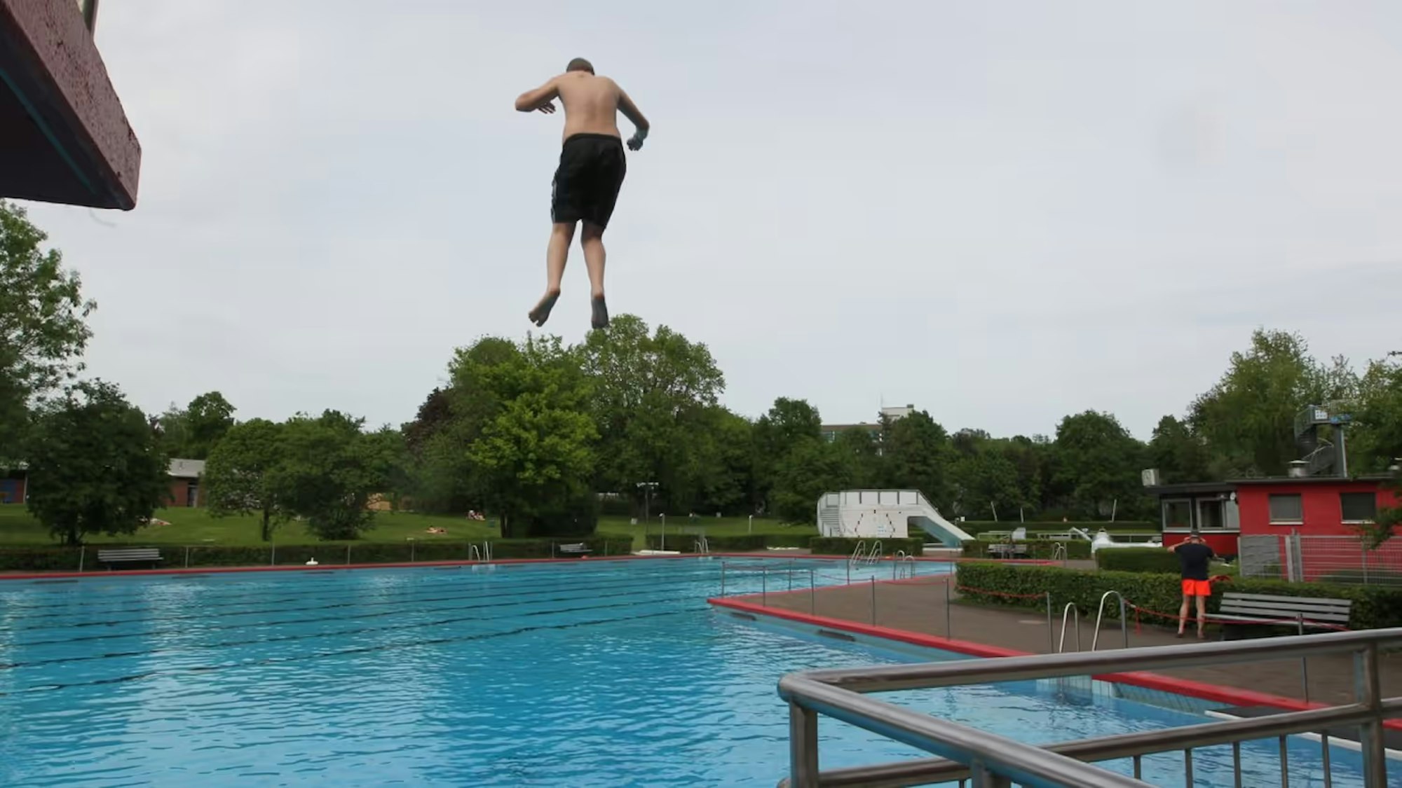 Eine Person springt in ein großes Schwimmbecken.