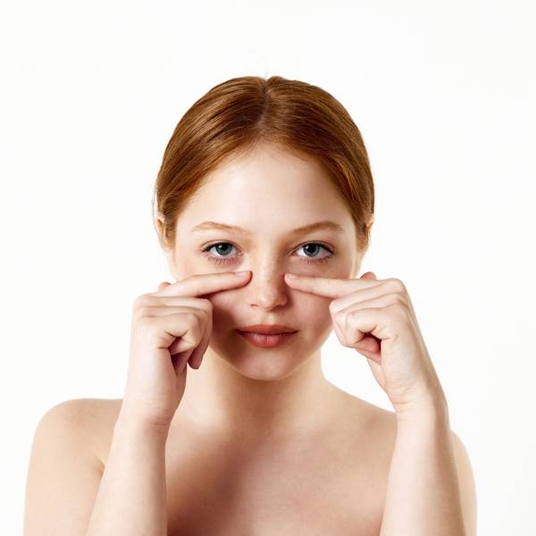 Portrait of tender, beautiful, young redhead girl touching nose against white studio background. Rhinoplasty, nose surgery. Concept of beauty, plastic surgery, rhinoplasty, cosmetology, health