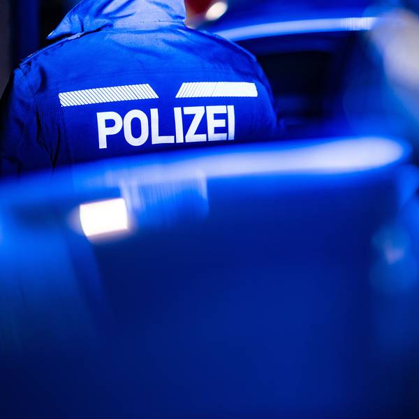 Ein Polizist steht neben einem Polizeiauto. (Symbolbild)