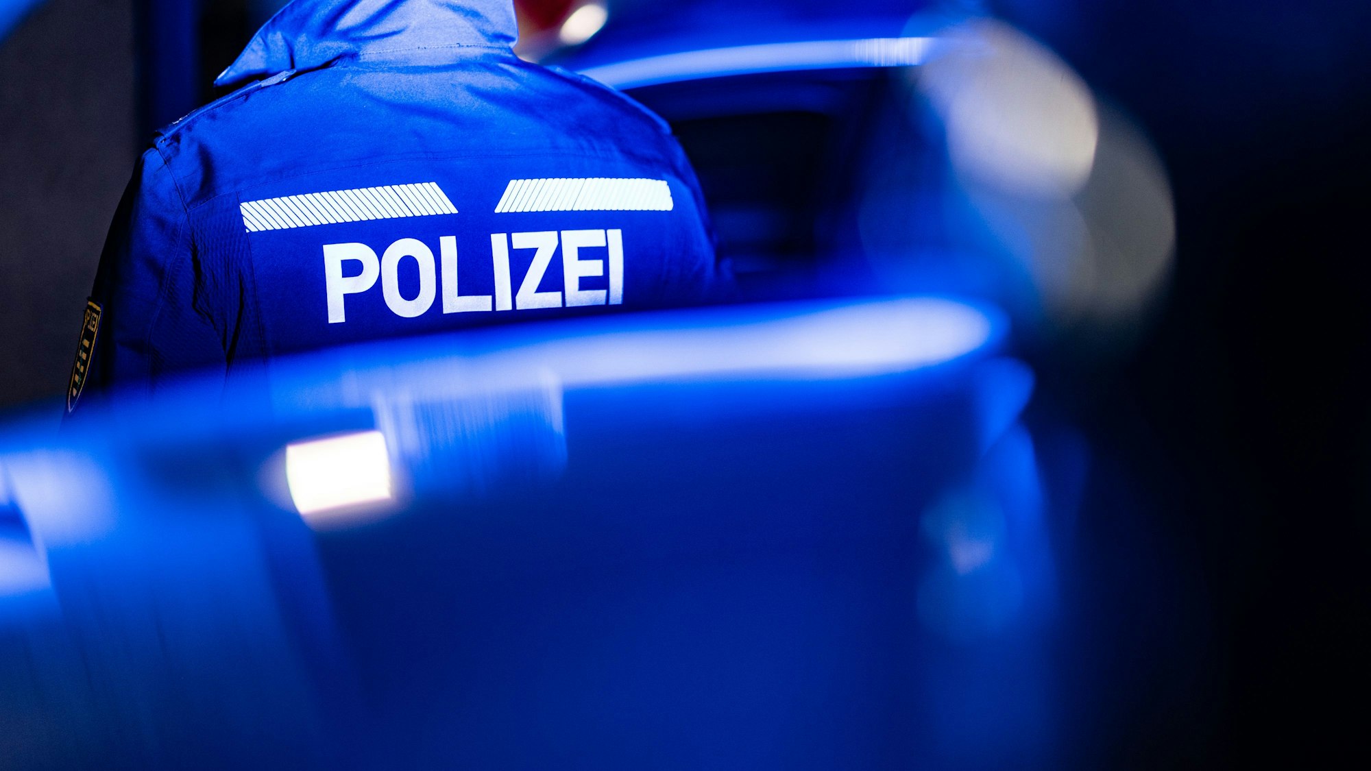 Ein Polizist steht neben einem Polizeiauto