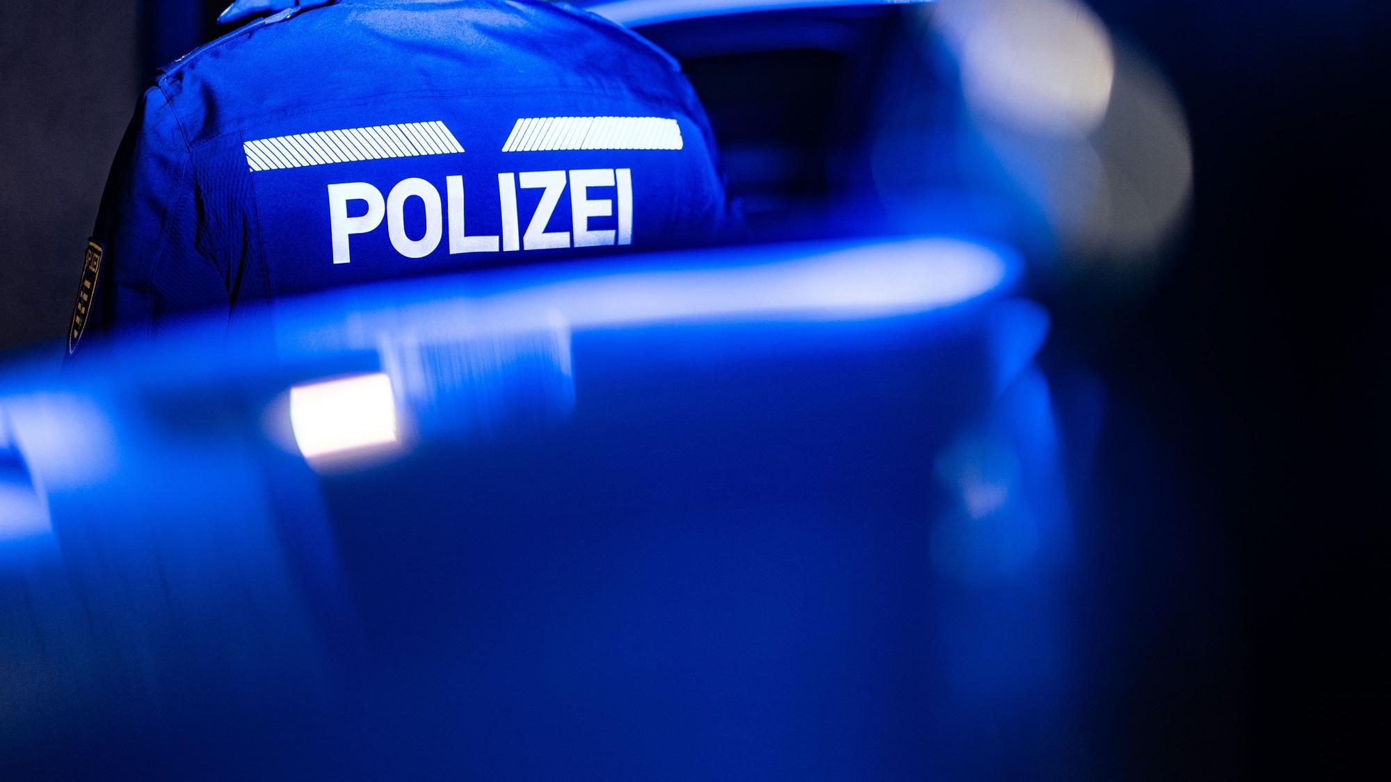 Ein Polizist steht neben einem Polizeiauto. (Symbolbild)