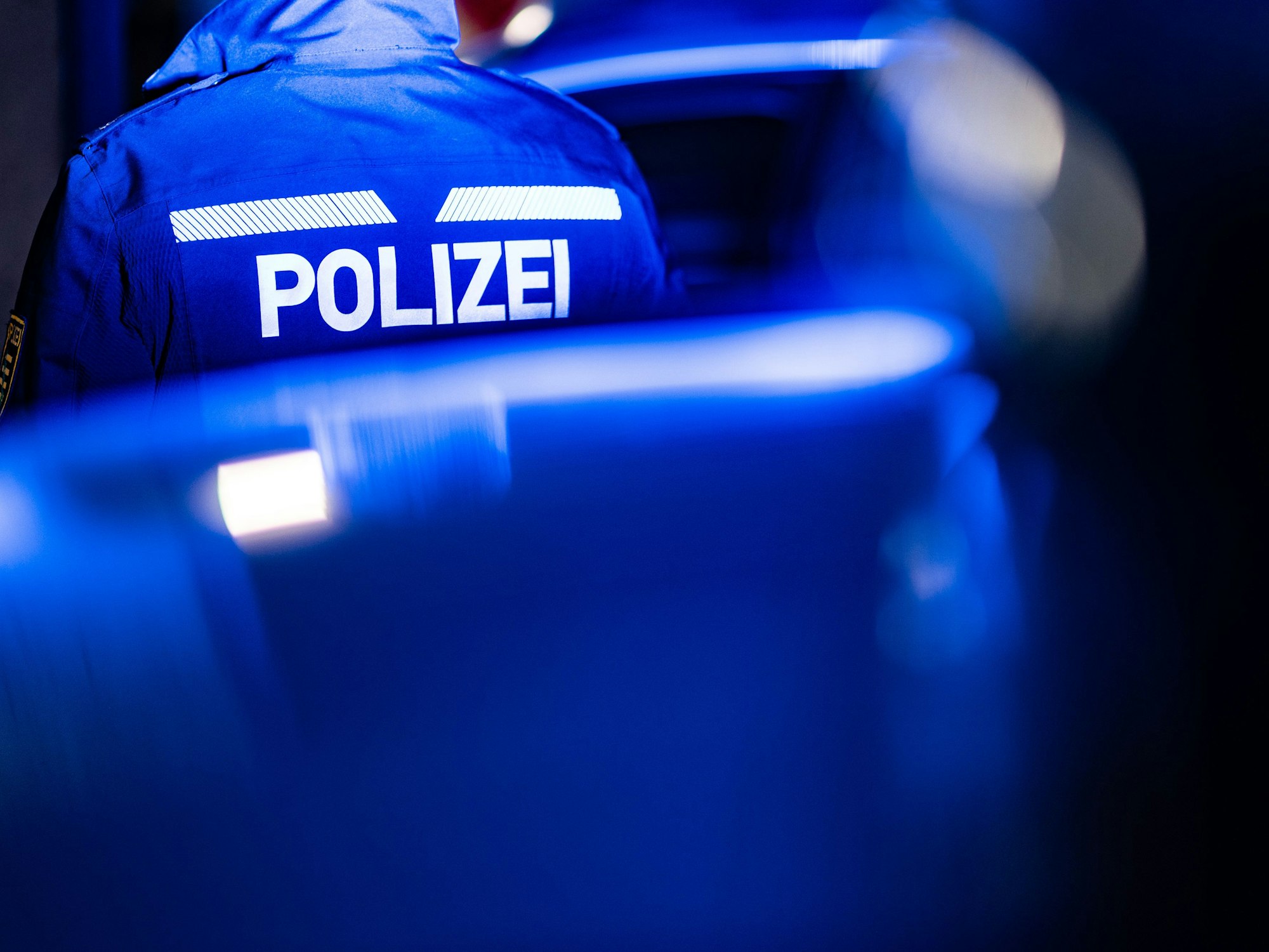 Ein Polizist steht neben einem Polizeiauto. (zu dpa: «Drogen, Waffen und viel Bargeld: Polizei ermittelt gegen drei Männer») +++ dpa-Bildfunk +++