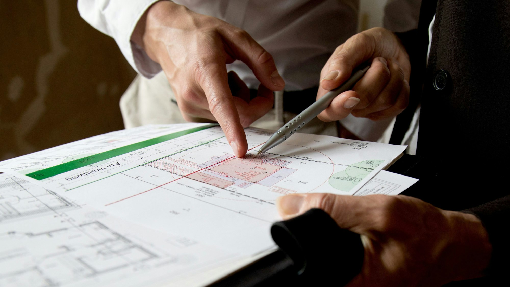 Zwei Hände zeigen auf den Grundriss einer Immobilie.