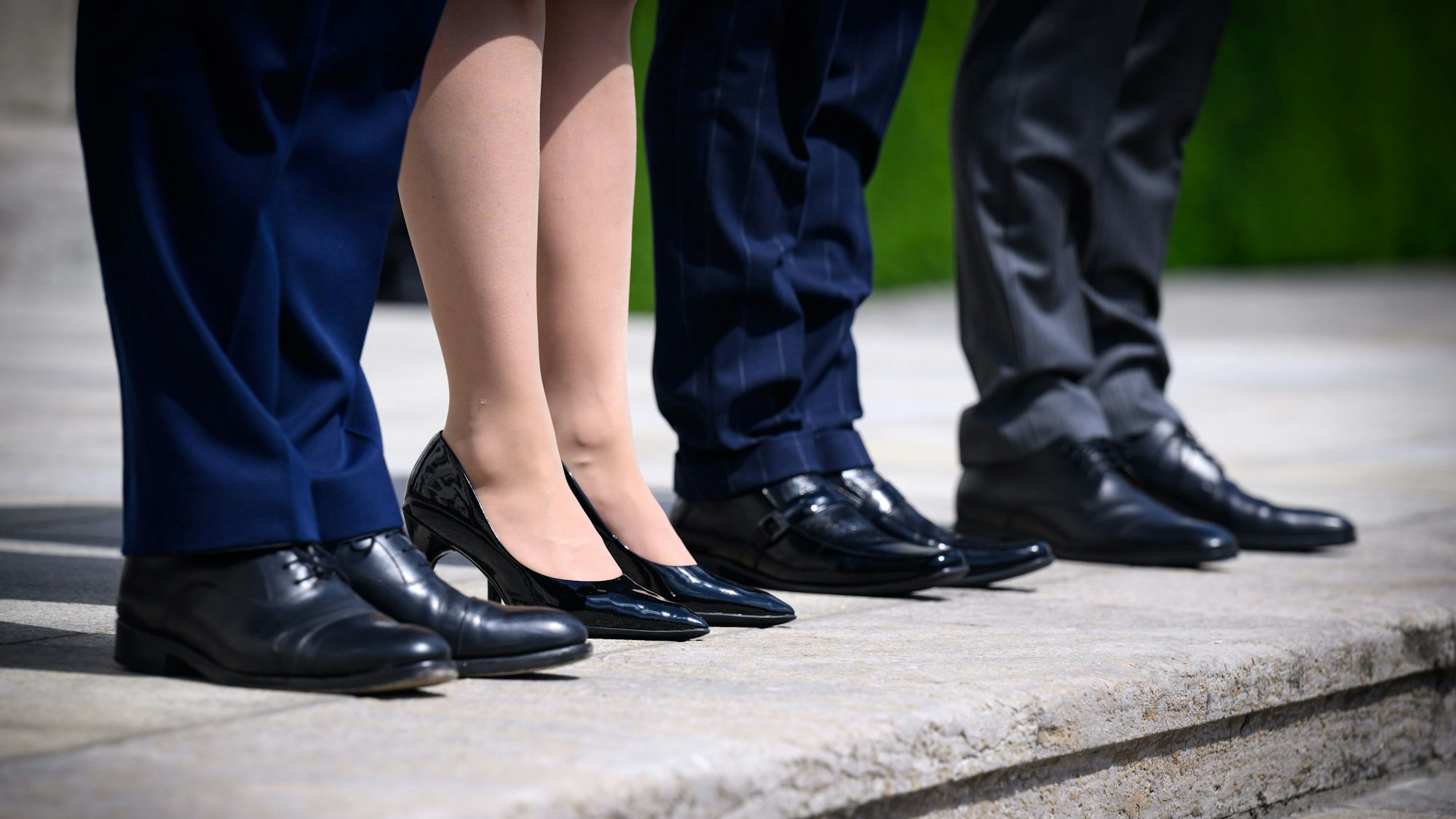 Eine Frau steht zwischen drei Männern in Anzügen auf den Treppenstufen von Schloss Bellevue.