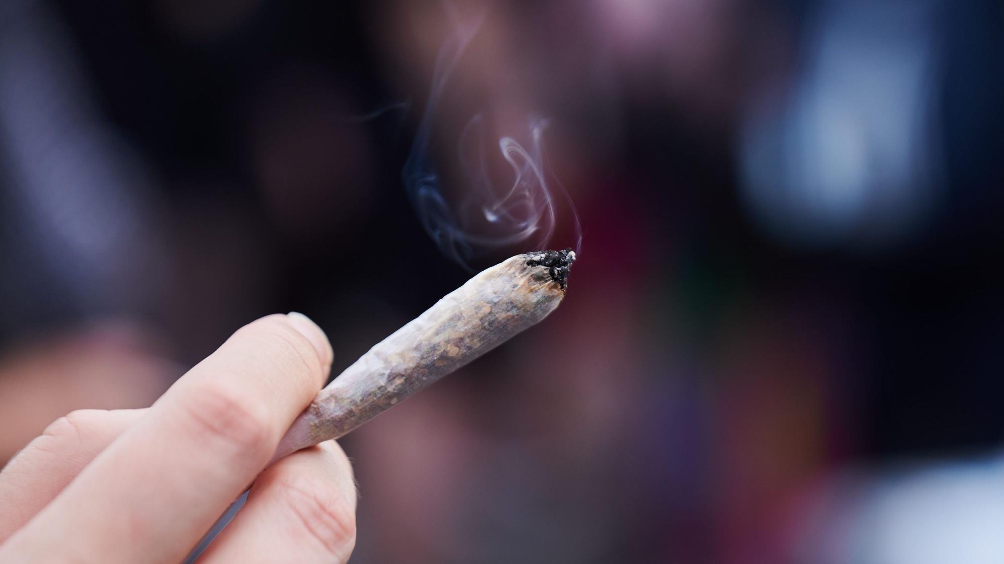 Eine Frau hält einen Joint in der Hand.