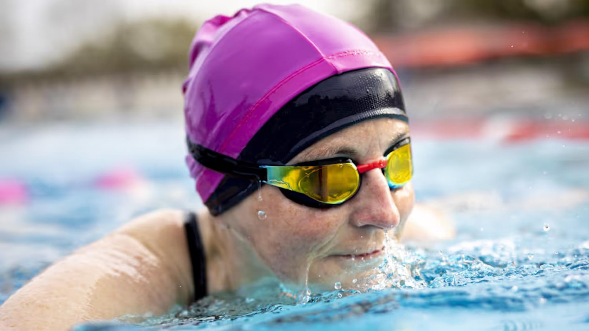 Eine Person mit Badekappe und Schwimmbrille im Wasser.