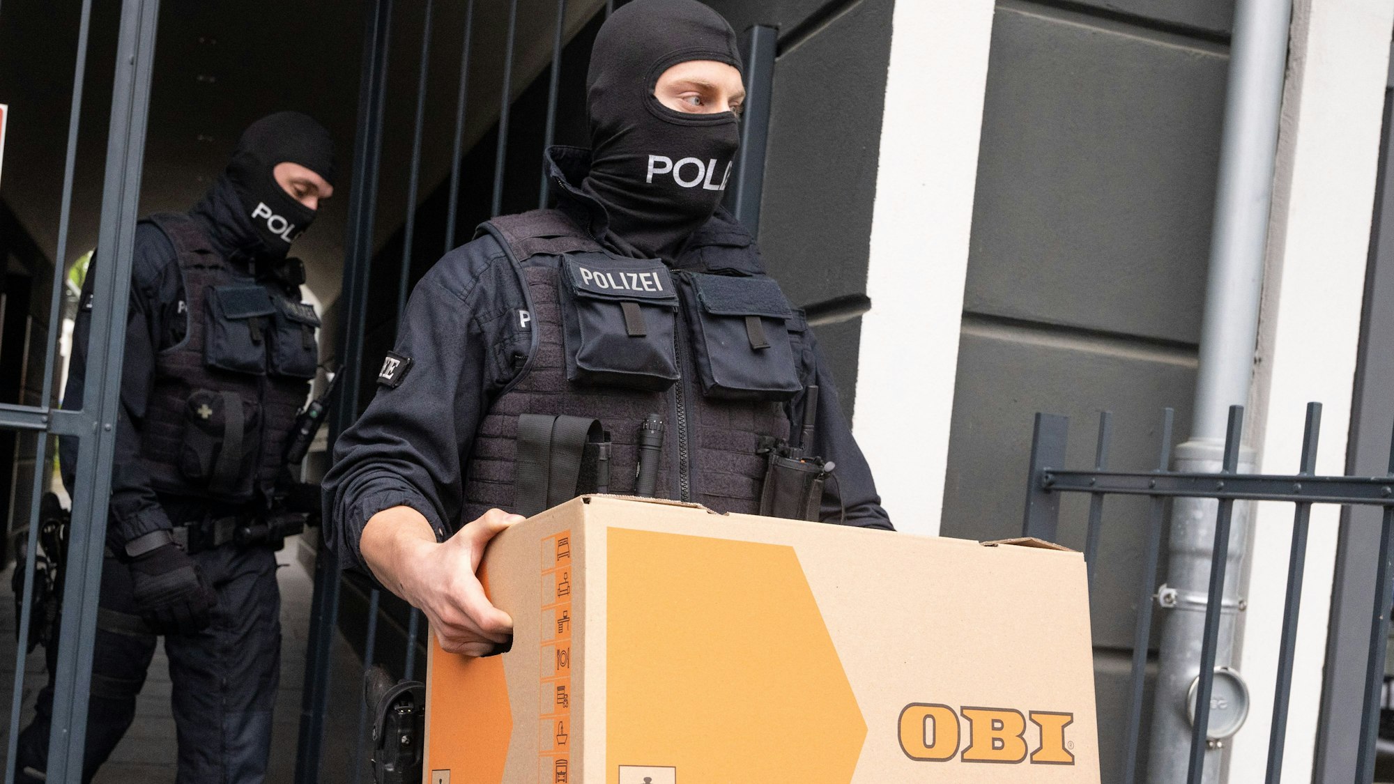Ein Polizist trägt im Rahmen einer Razzia gegen Schleuser ein Karton aus einem Gebäude. Die am Mittwoch in acht Bundesländern ausgeführte Razzia gegen Schleuser ist am Donnerstag in Nordrhein-Westfalen fortgesetzt worden. Etwa 600 Beamte von Bundespolizei und Staatsanwaltschaft seien im Einsatz, sagte ein Sprecher der Bundespolizei. +++ dpa-Bildfunk +++