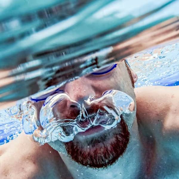 Eine Person mit Schwimmbrille unter Wasser.