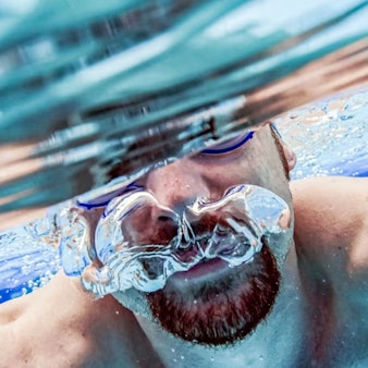 Eine Person mit Schwimmbrille unter Wasser.
