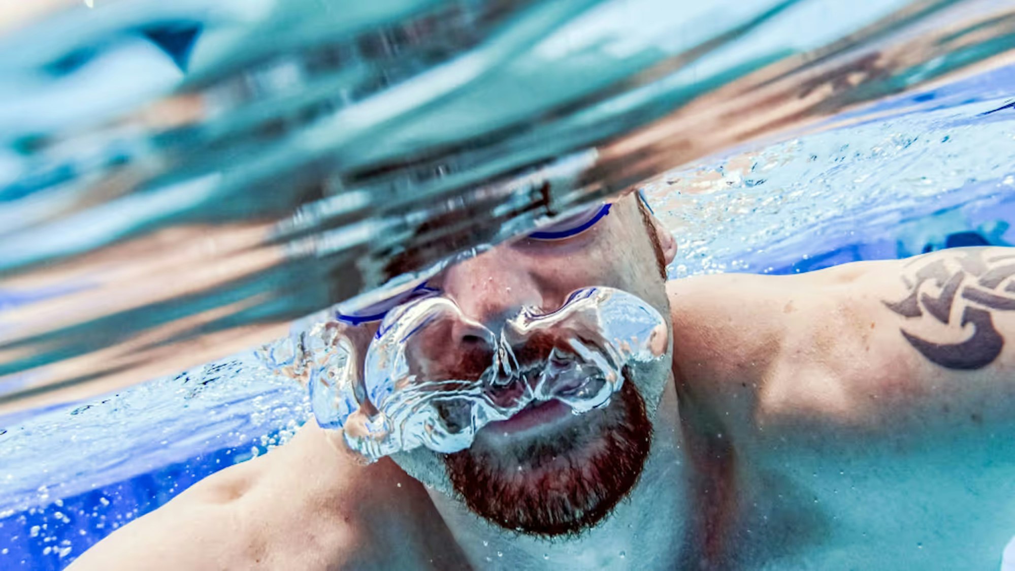 Eine Person mit Schwimmbrille unter Wasser.