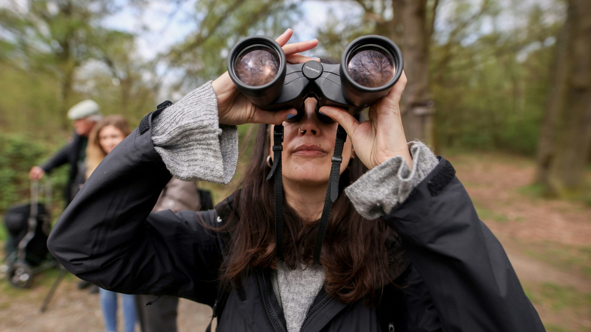 Im Vordergrund ist Jana Romero mit Fernglas zu sehen, verschwommen dahinter Michelle Etienne und Volker Brinkmann.