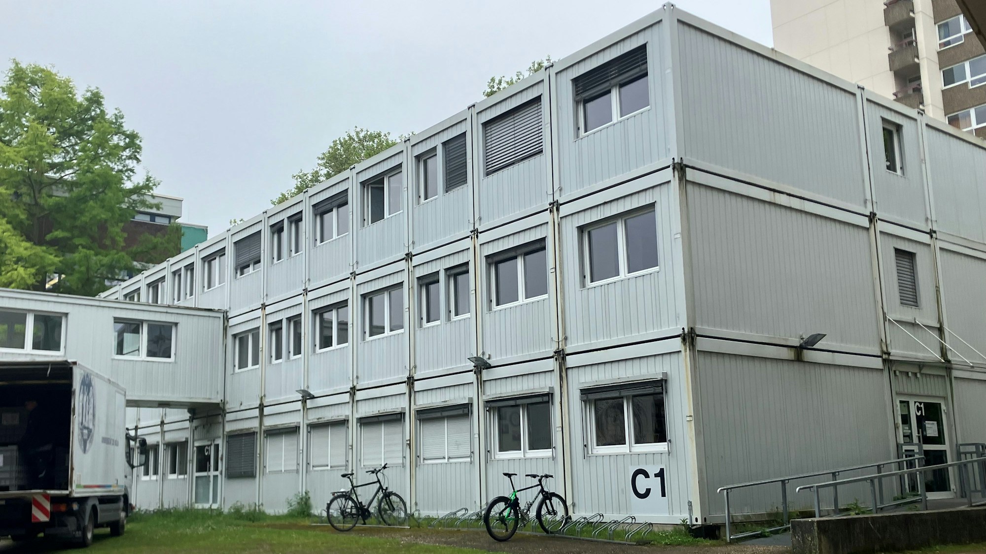 Ein Containerbau mit drei Stockwerken steht auf einer Fläche an der Uni Köln