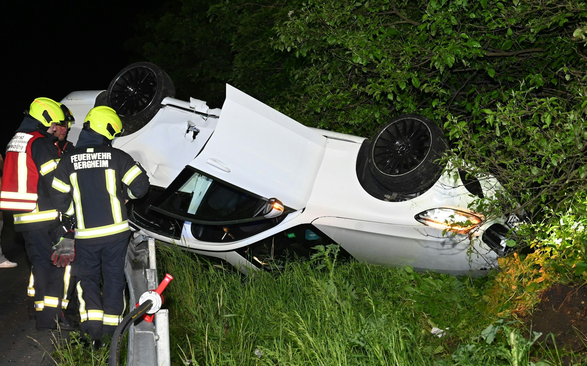 Auf dem Foto sind Feuerwehrleute an dem Unfallwagen zu sehen, der auf dem Dach liegt.