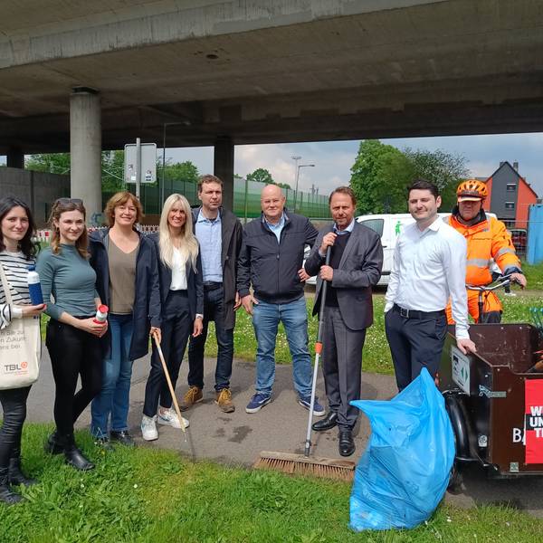 Vier Frauen und fünf Männer posieren zusammen für ein Foto. In den Händen halten sie Reinigungswerkzeuge.