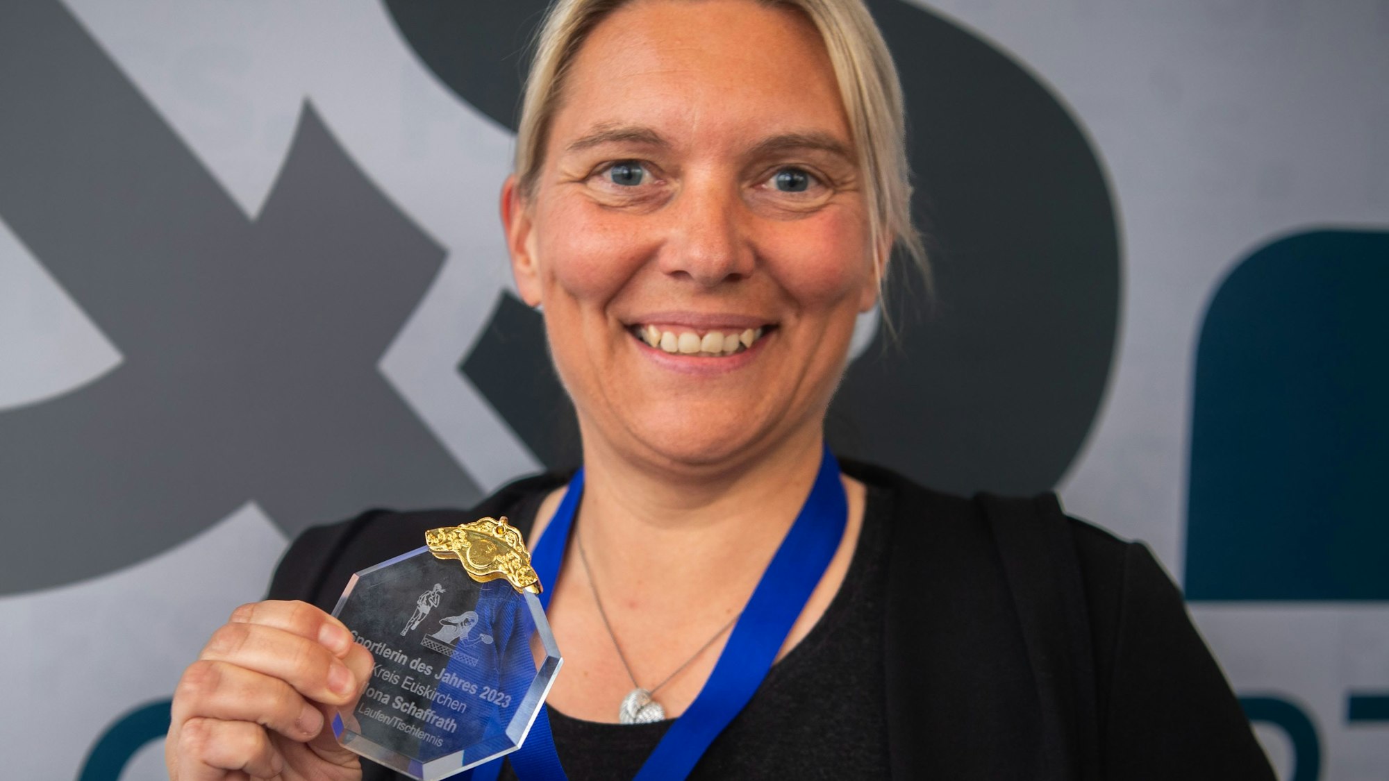 Ilona Schaffrath hält ihre Medaille in die Kamera und strahlt.