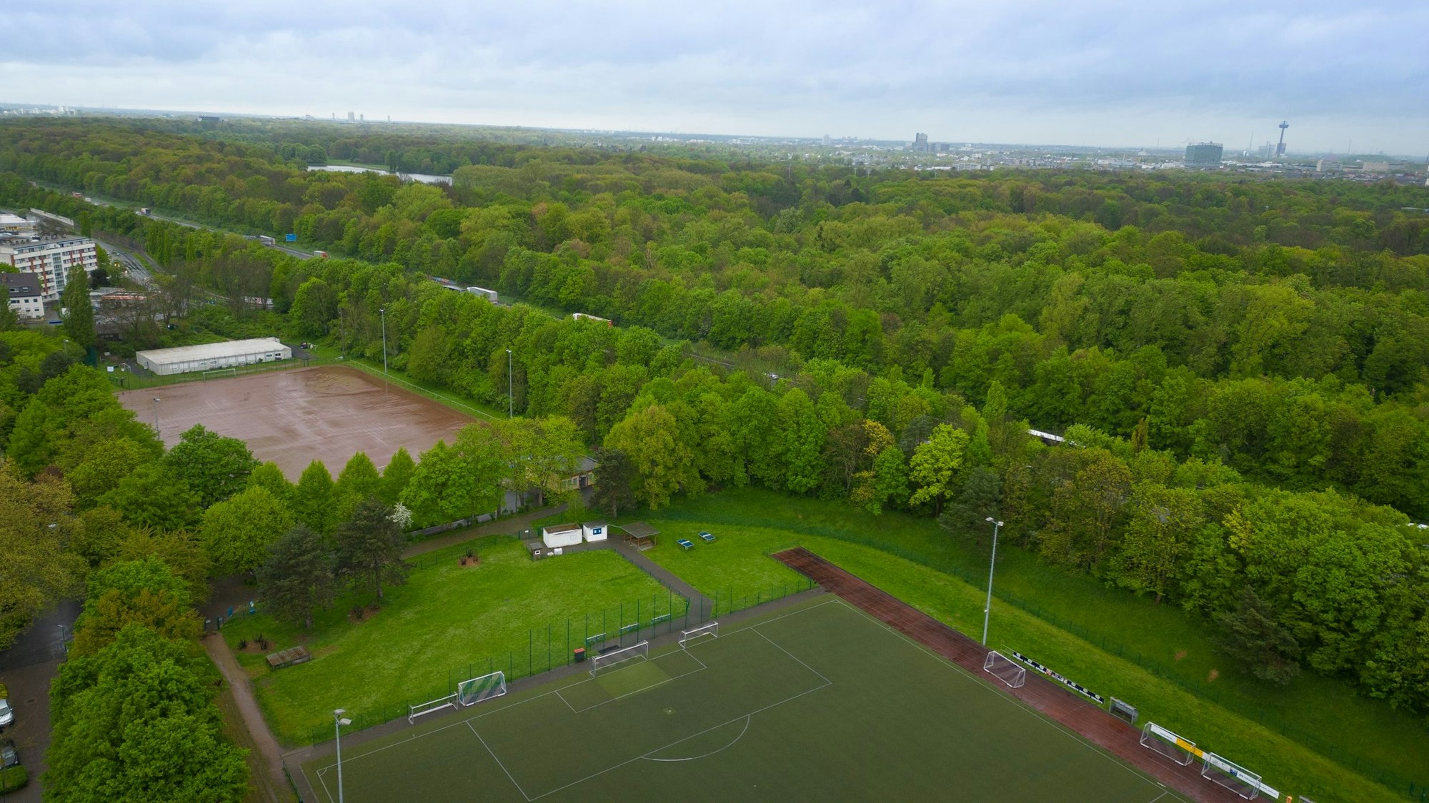 Das Luftbild zeigt einen Aschenplatz und einen Kunstrasenplatz, im Hintergrund die Autobahn und den Grüngürtel.