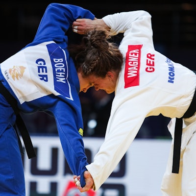 Die Judoka Alina Böhm und Anna-Maria Wagner während eines Kampfes, ihre Köpfe stoßen aneinander. Böhm trägt einen blauen Judoanzug, Wagner einen weißen.