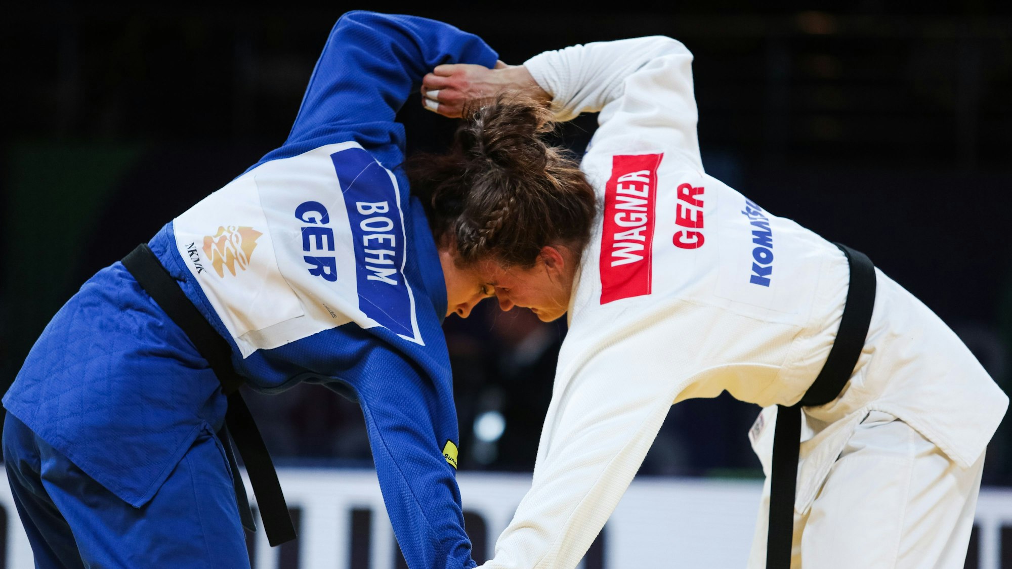 Die Judoka Alina Böhm und Anna-Maria Wagner während eines Kampfes, ihre Köpfe stoßen aneinander. Böhm trägt einen blauen Judoanzug, Wagner einen weißen.