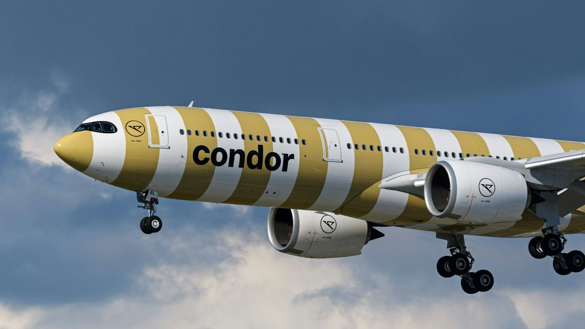 Ein Airbus A330 der deutschen Fluggesellschaft Condor in gold-weißer Lackierung kurz nach dem Start vor mehreren dunklen Wolken. (Symbolbild)