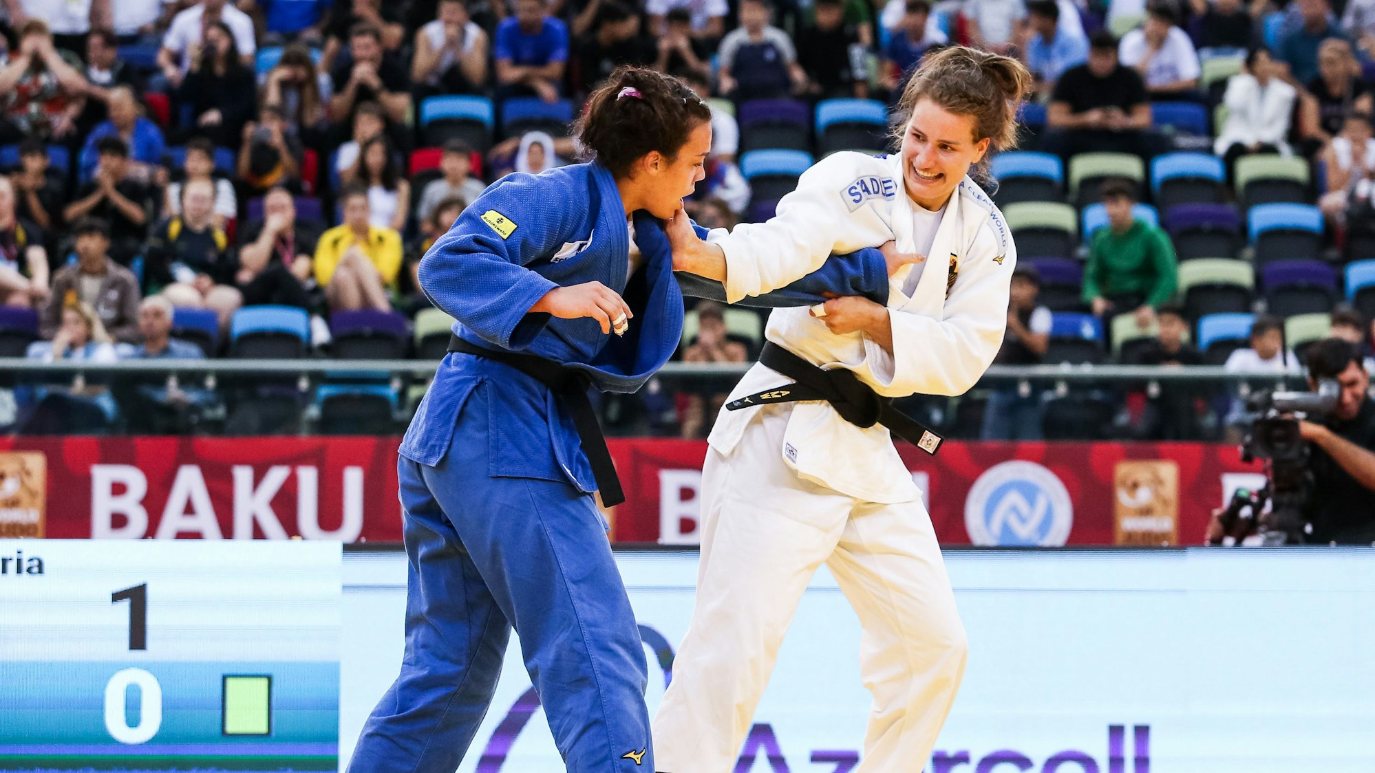 Die Judoka Alina Böhm und Anna-Maria Wagner während eines Kampfes beim Grand Slam in Baku. Böhm trägt einen blauen Judoanzug, Wagner einen weißen. Sie greifen sich gegenseitig an den Jacken.