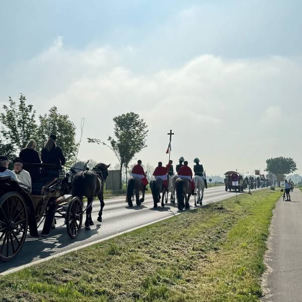 Zu sehen sind Reiter und Kutschen, die auf einer Straße unterwegs sind.