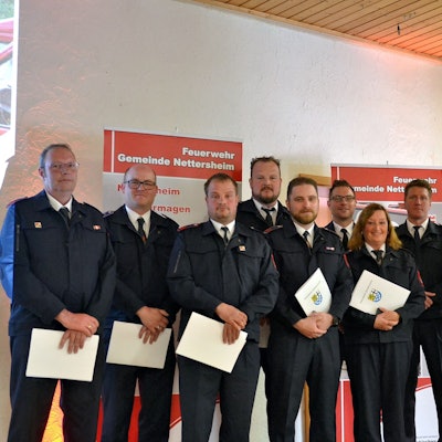 Zahlreiche Feuerwehrleute aus Nettersheim halten Urkunden mit dem Gemeindewappen in den Händen. Rechts steht Bürgermeister Norbert Crump.