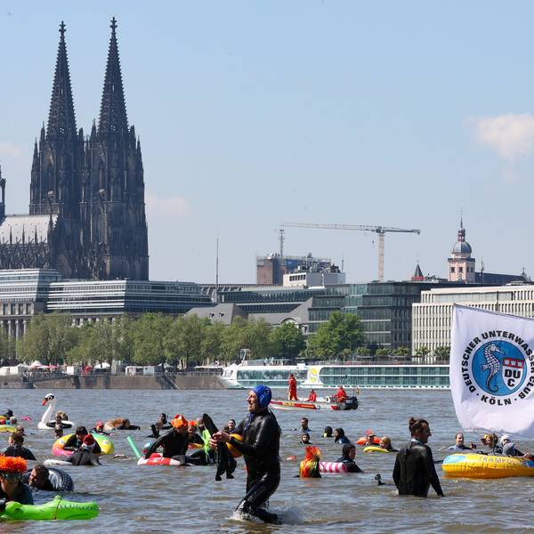 Menschen schwimmen im Rhein, im Hintergrund der Kölner Dom