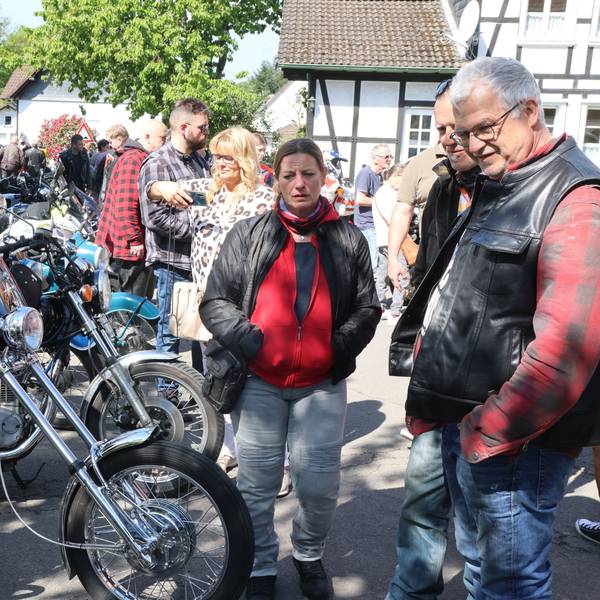 Viele Menschen stehen um eine Reihe von Motorrädern.