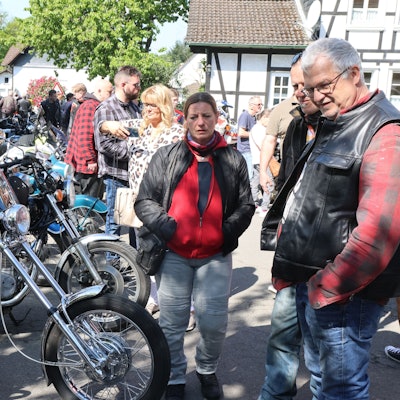 Viele Menschen stehen um eine Reihe von Motorrädern.