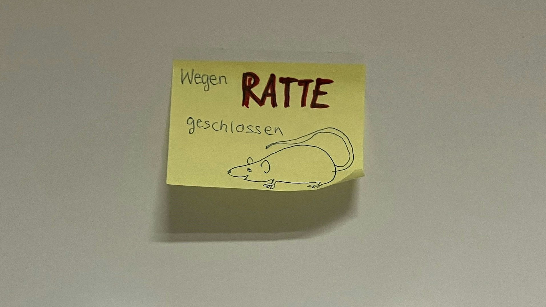 Ein gelber Post-It-Zettel zeigt den Hinweis "Wegen Ratte geschlossen", daneben ist das Bild einer Ratte gezeichnet.