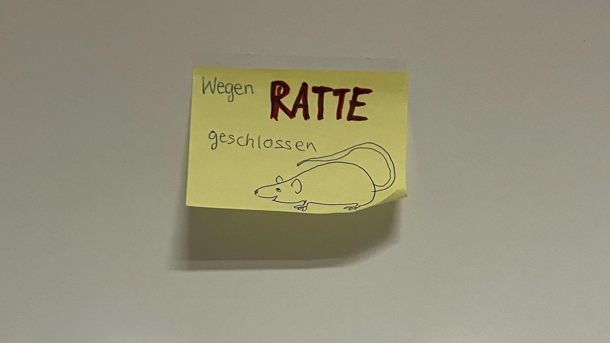 Ein gelber Post-It-Zettel zeigt den Hinweis "Wegen Ratte geschlossen", daneben ist das Bild einer Ratte gezeichnet.