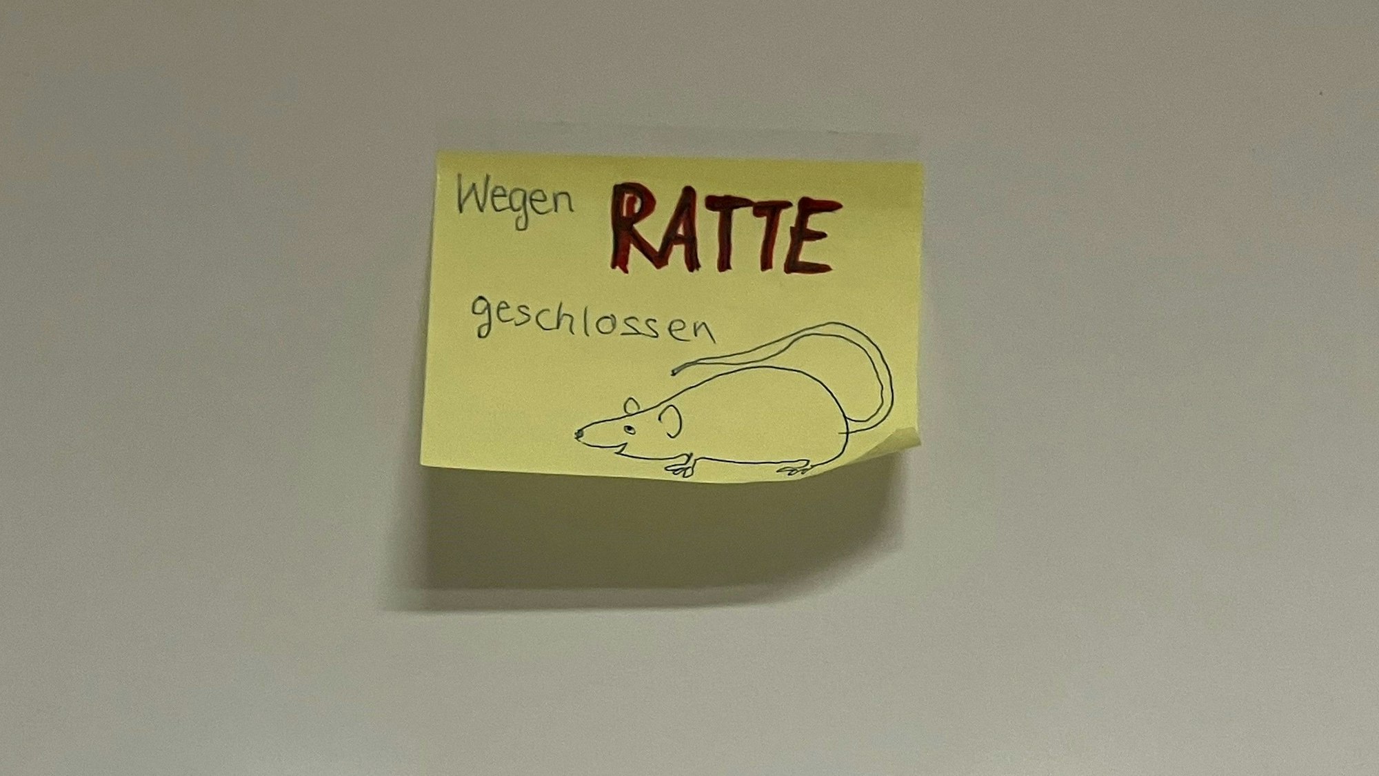 Ein gelber Post-It-Zettel zeigt den Hinweis "Wegen Ratte geschlossen", daneben ist das Bild einer Ratte gezeichnet.
