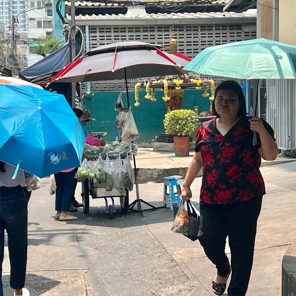 Thailand, Bangkok: Menschen schützen sich in Bangkok mit Schirmen vor der extremen Hitze und vor der Sonne.