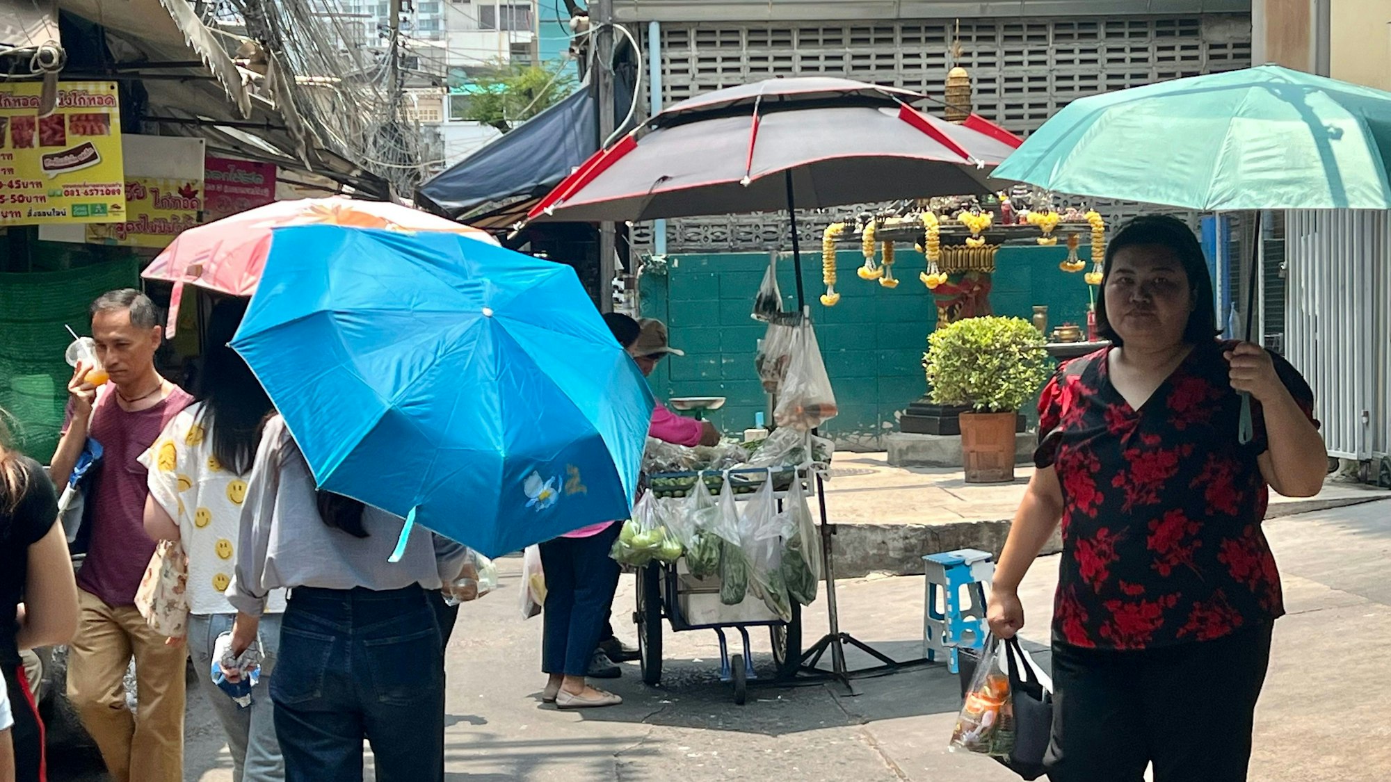 Thailand, Bangkok: Menschen schützen sich in Bangkok mit Schirmen vor der extremen Hitze und vor der Sonne.