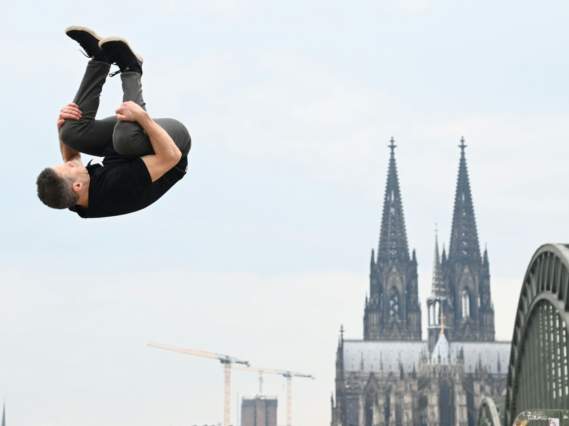 Ein Mann springt ein Salto vor dem Dom.