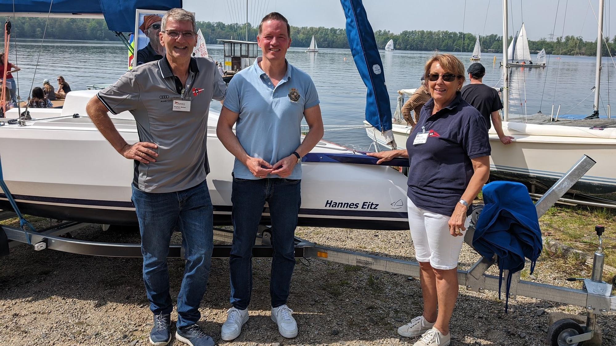 Drei Personen stehen vor einem Boot.