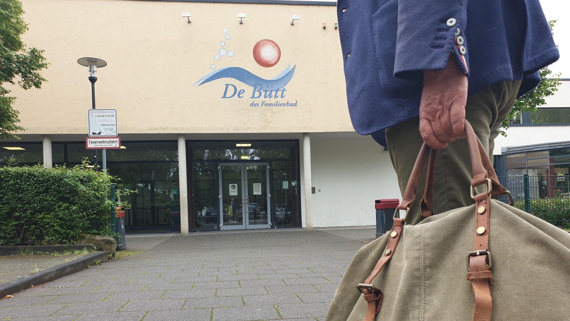 Ein Mann mit einer Sporttasche vor dem Eingang des Familienbads in Hürth.